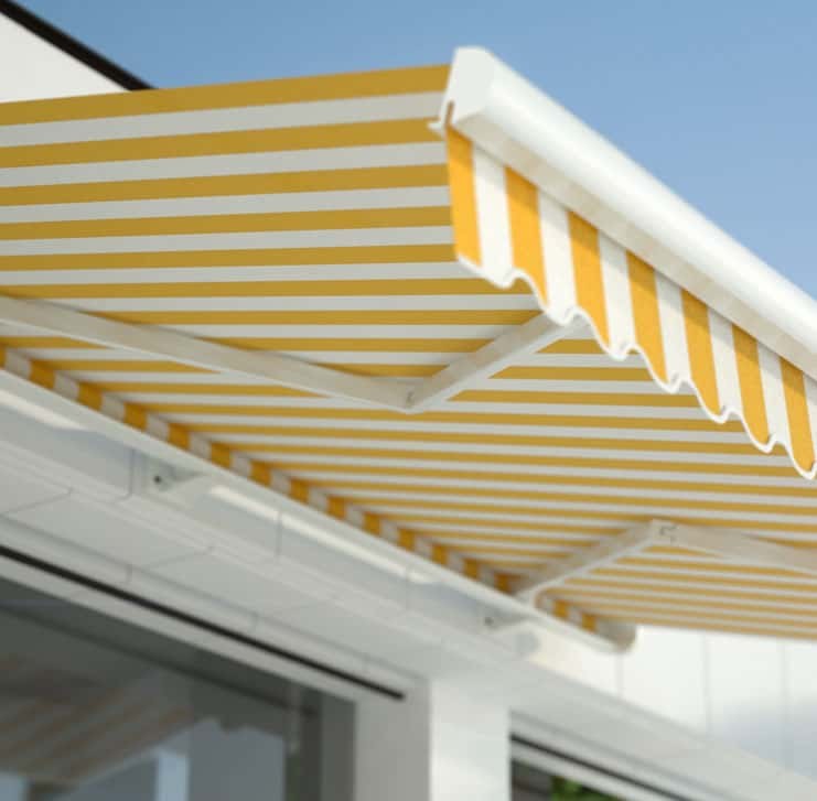 Ausgefahrene gelb-weiß gestreifte Markise über der Terrasse