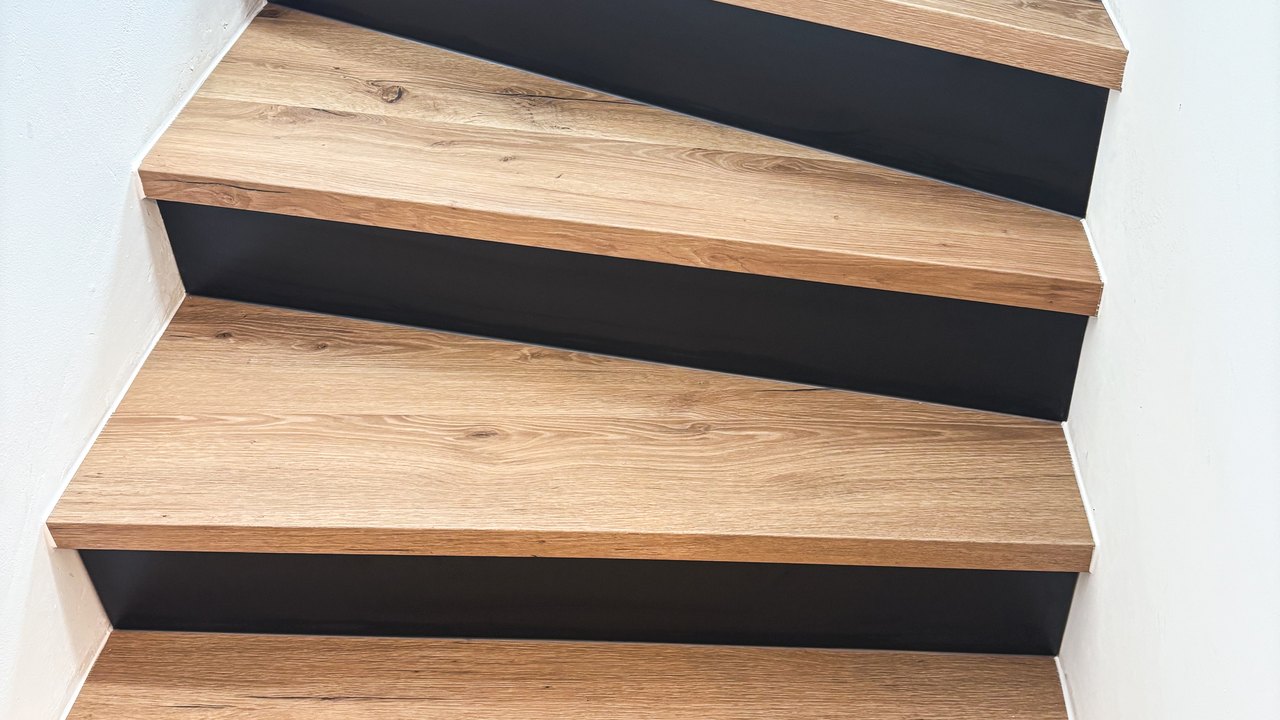 Renovierte Wendeltreppe mit Vinyl-Stufen in Holzoptik und schwarzen Setzstufen